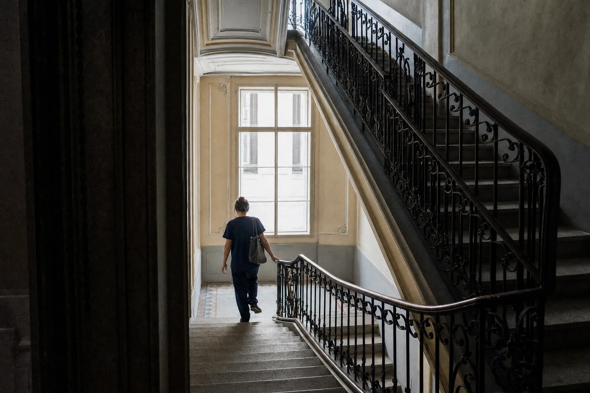 Eine Pflegekraft von MDM Care verlässt mit ihrer Pflegetasche das Stiegenhaus eines Wiener Wohnhauses auf dem Weg zum nächsten Einsatz.