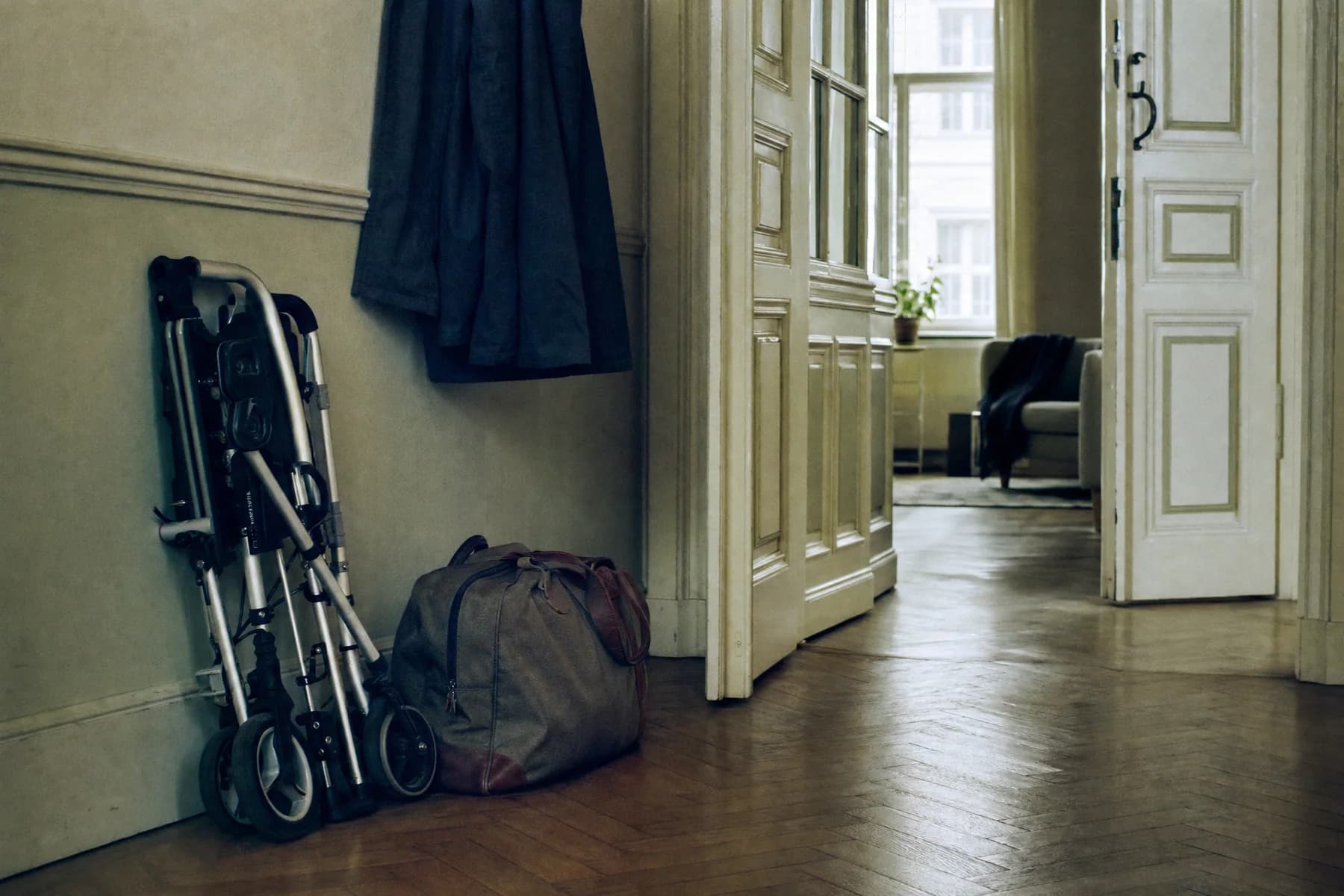 Ein Rollator und eine gepackte Tasche stehen im Vorzimmer einer Wiener Altbauwohnung, im Hintergrund eine offene Wohnungstür.